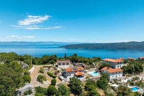 Ein Küstenwohngebiet mit Häusern, einem Schwimmbad und Blick auf das Meer.