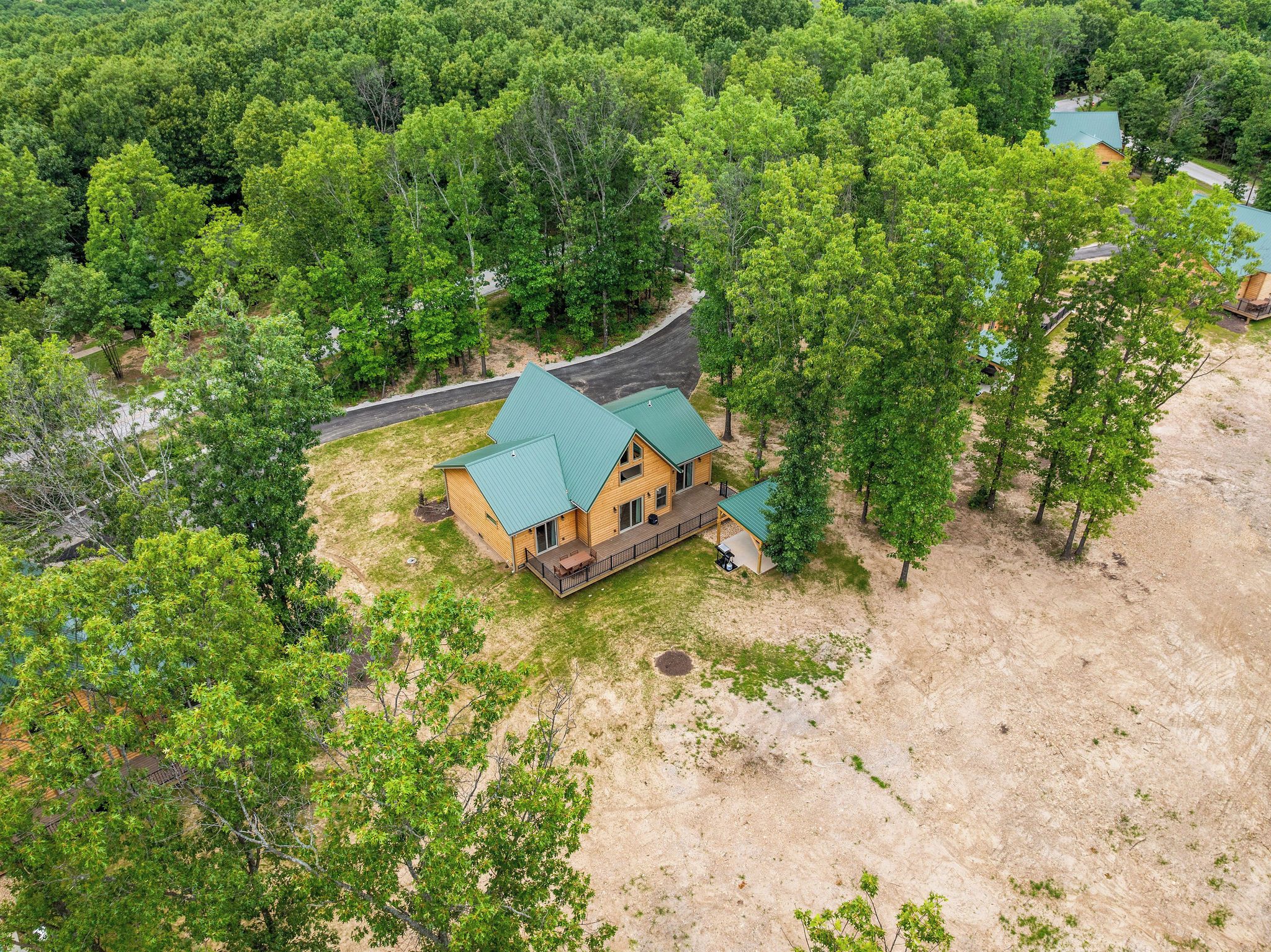 A wooden cabin with a green roof surrounded by dense forest.