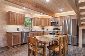 Une cuisine moderne avec des meubles en bois, des appareils en acier inoxydable et une table à manger avec un plateau en verre.
