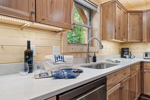 A kitchen with wooden cabinets, a stainless steel sink, a coffee maker, and a dishwasher.