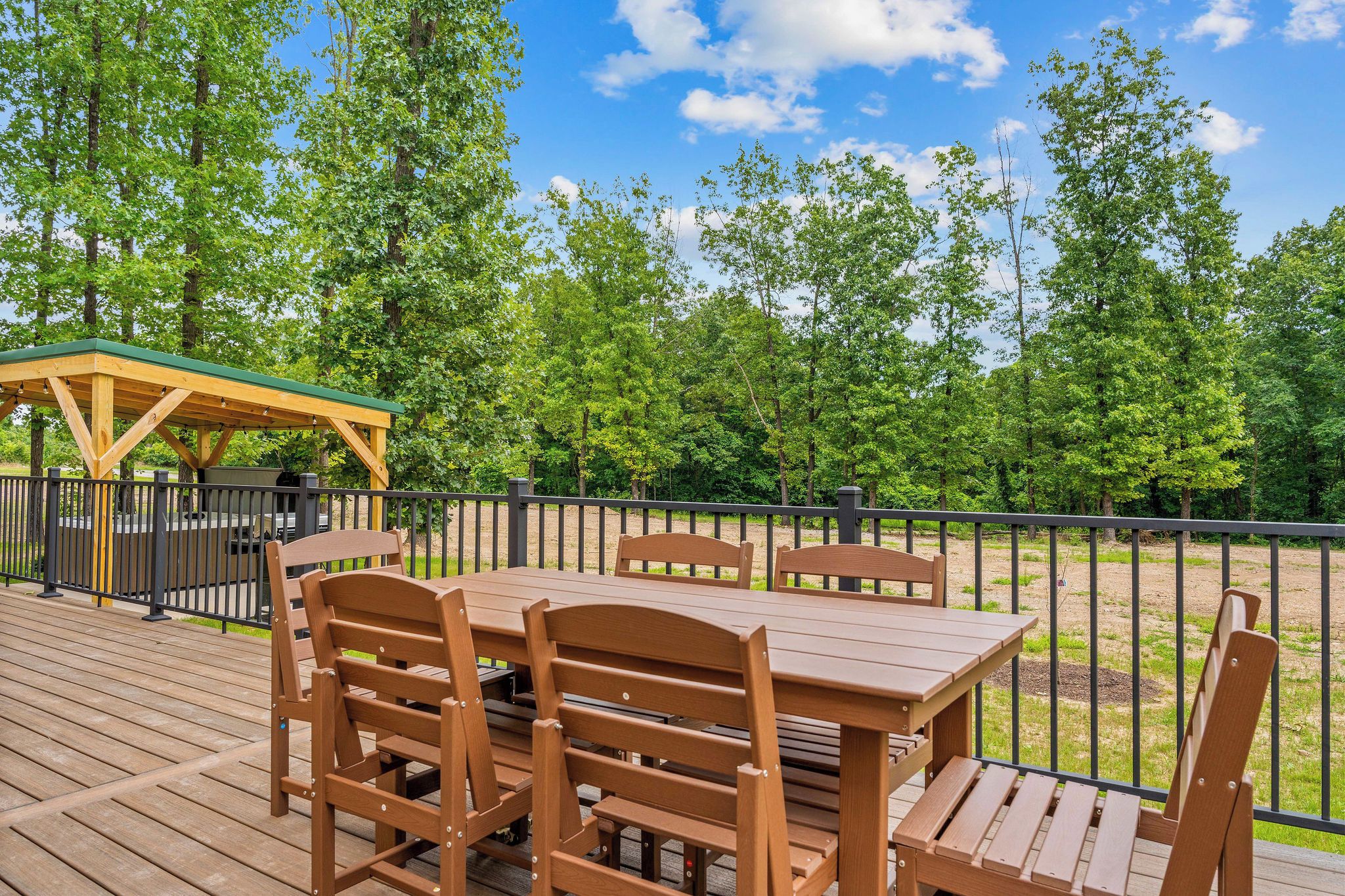 An outdoor deck with wooden furniture and a covered seating area.