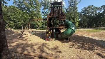 A playground with a wooden play structure, including a slide and climbing elements.