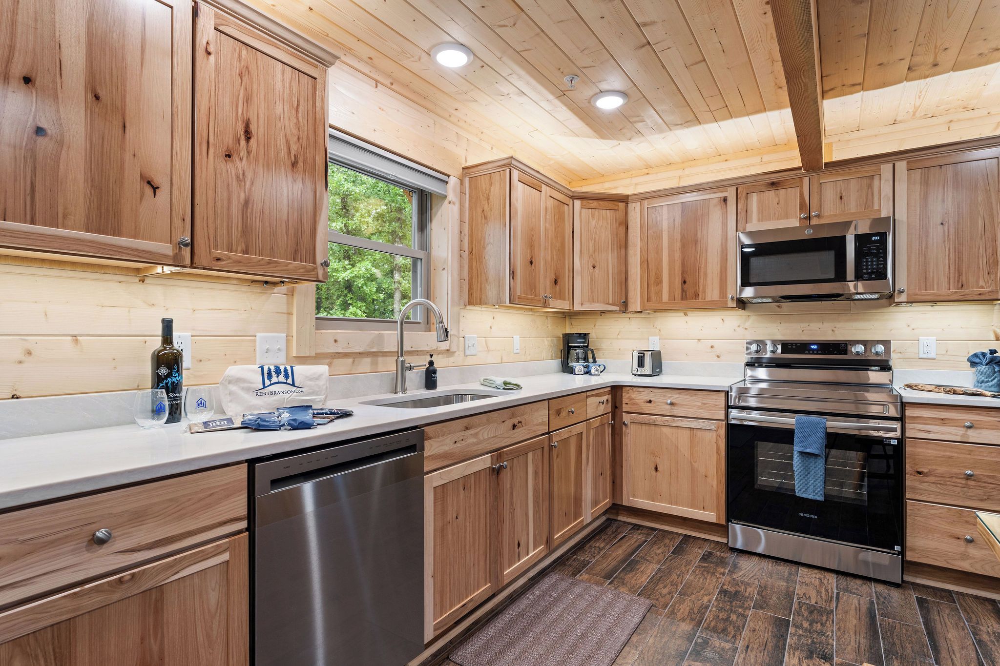 A modern kitchen with wooden cabinets, stainless steel appliances, and a window providing natural light.
