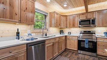 A modern kitchen with wooden cabinets, stainless steel appliances, and a window providing natural light.