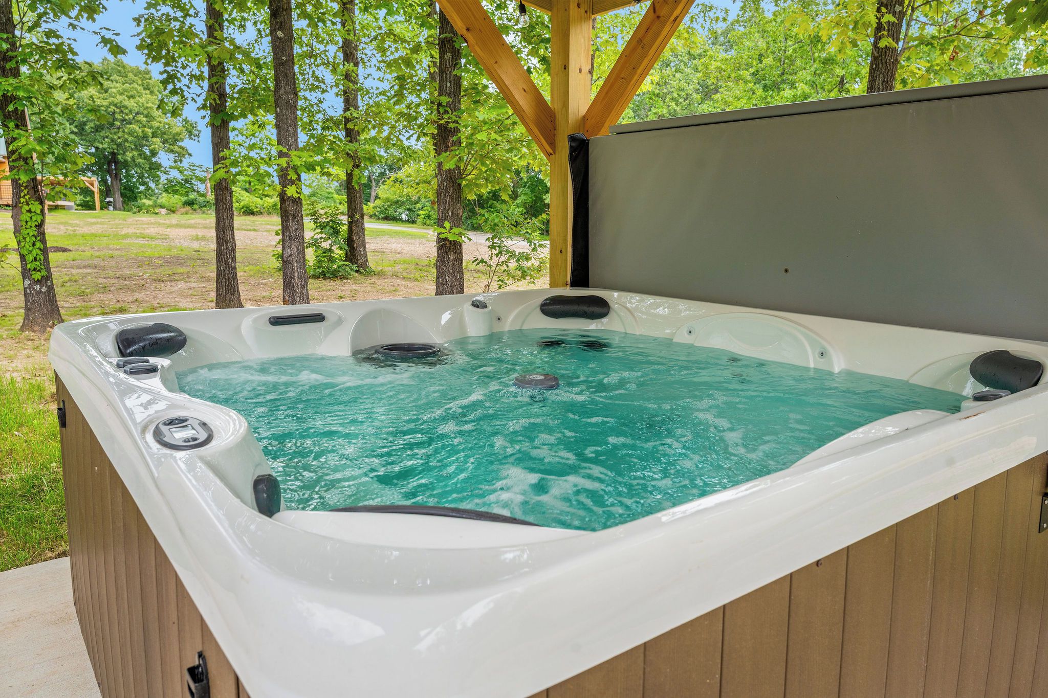 A hot tub with a wooden deck and a view of trees.