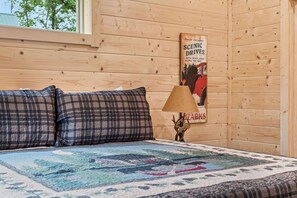 A room with a bed, a poster, a lamp, and a bear antler decoration.