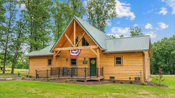 A log cabin with a porch, a flag, and a wreath.