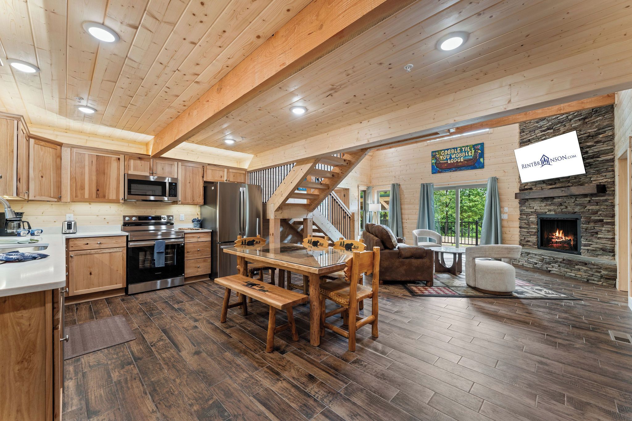 A spacious kitchen with modern appliances, a dining area with wooden furniture, and a stone fireplace.