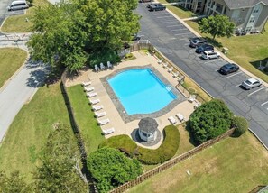 Eine Vogelperspektive eines Hotels mit Swimmingpool, umgeben von Liegestühlen, einem Pavillon und einem Parkplatz.