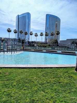 Ein Swimmingpool mit Palmen und modernen Gebäuden im Hintergrund.