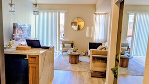 A modern living room with a kitchen area, a round mirror, and a dining table with chairs. - Gaslamp  Studio, Modern&Serene within walking distance to Petco Park and Harbor. (San Diego)