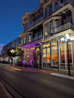A historic building with ornate architecture, a covered outdoor seating area, and large windows displaying interior lighting. - Gaslamp  Studio, Modern&Serene within walking distance to Petco Park and Harbor. (San Diego)