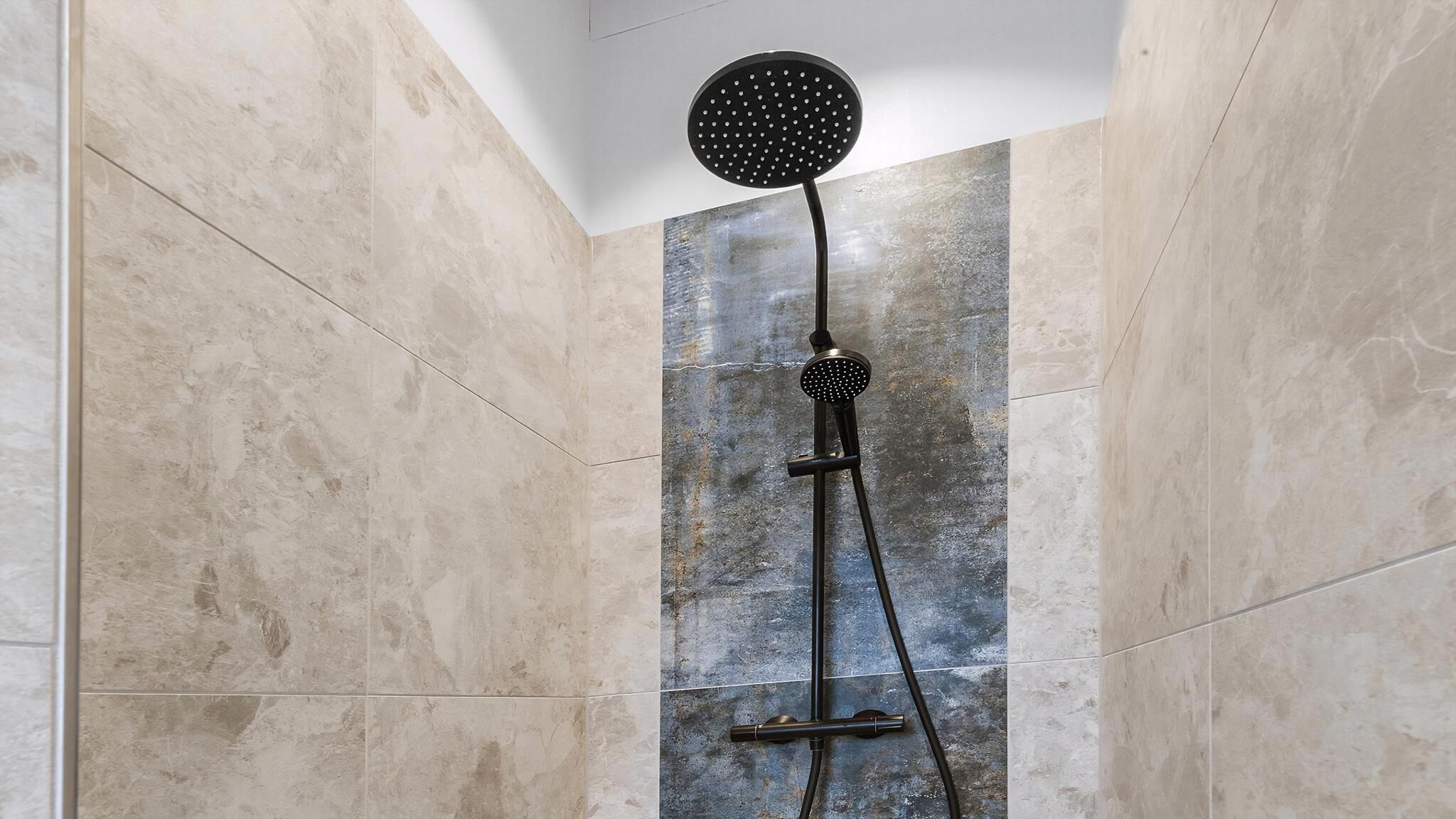 A shower with a round head and a vertical rain shower head.