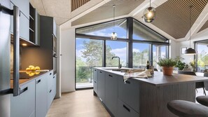 A modern kitchen with a large island, a built-in oven, and a view of the outdoors. - VillaVilla 968 - Ebeltoft, Østjylland (Ebeltoft)