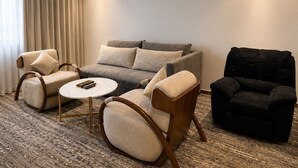 Una sala moderna con un sofá, dos sillones, una mesa de centro y un sillón negro.