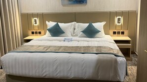 Habitación de hotel con una cama grande, dos mesitas de noche, una obra de arte colgada en la pared y piso alfombrado.