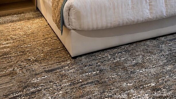 Una habitación de hotel moderna con una cama grande, un cabecero de madera y lámparas de noche.