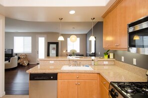 Eine moderne Küche mit Granit Arbeitsplatten, Edelstahlgeräten und Holzschränken.