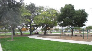 Een park met een speeltuin, picknicktafels en bomen.
