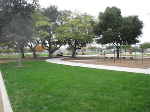 Ein Park mit einem Spielplatz, Picknicktischen und Bäumen.