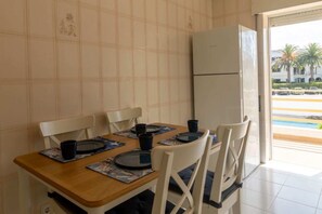 Ein Essbereich mit einem Holztisch, weißen Stühlen und einem Kühlschrank.