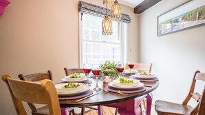 A dining table set with plates, glasses, and a potted plant. - Barnaby Cottage, Southwold (Southwold)