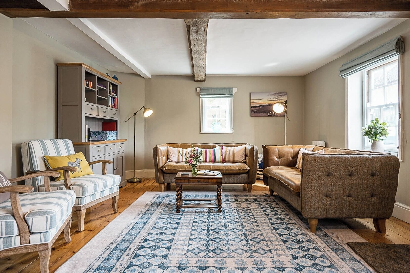 A cozy living room with a sofa, armchairs, a coffee table, and a bookshelf.