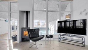 A modern living room with a fireplace, a television, and a large window. - VillaVilla 982 - Vedersø Klit, Vestjylland (Ulfborg)