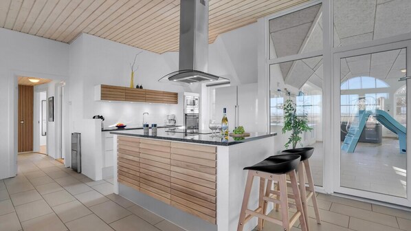 Una cocina moderna con una isla central, armarios de madera y un amplio ventanal con vistas al exterior.