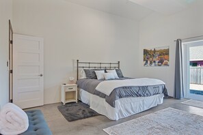 Ein Schlafzimmer mit einem Bett, einem Nachttisch, einer Bank, einer Tür und einem Fenster.