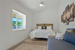 A bedroom with a bed, a window, a ceiling fan, and a wall-mounted artwork. - Kenwood Wine Country Cottage (Kenwood)