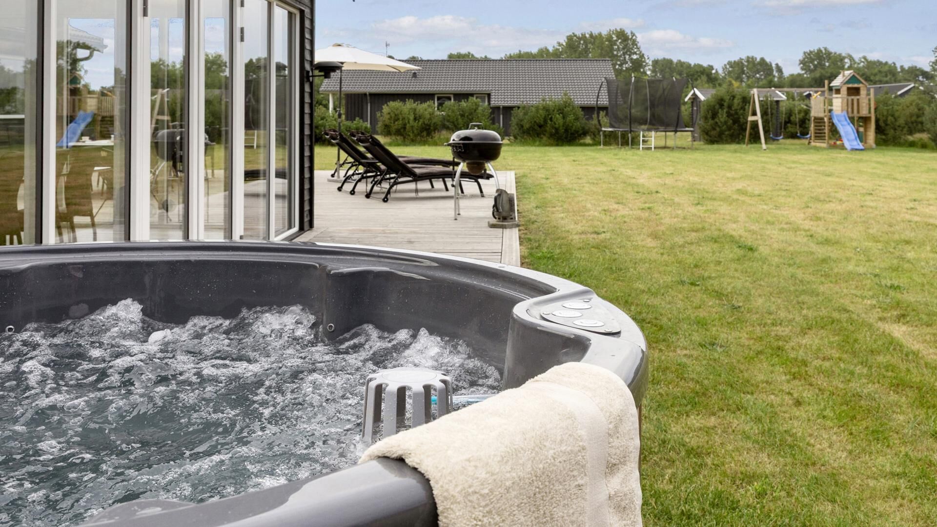 A hot tub with a view of a deck and outdoor play area.