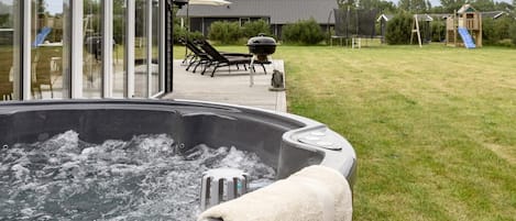 Un bain à remous avec vue sur une terrasse et un espace de jeux extérieur.