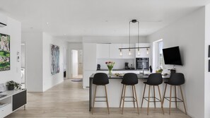 Eine moderne Küche mit Kochinsel, Barhocker und Flachbildfernseher.