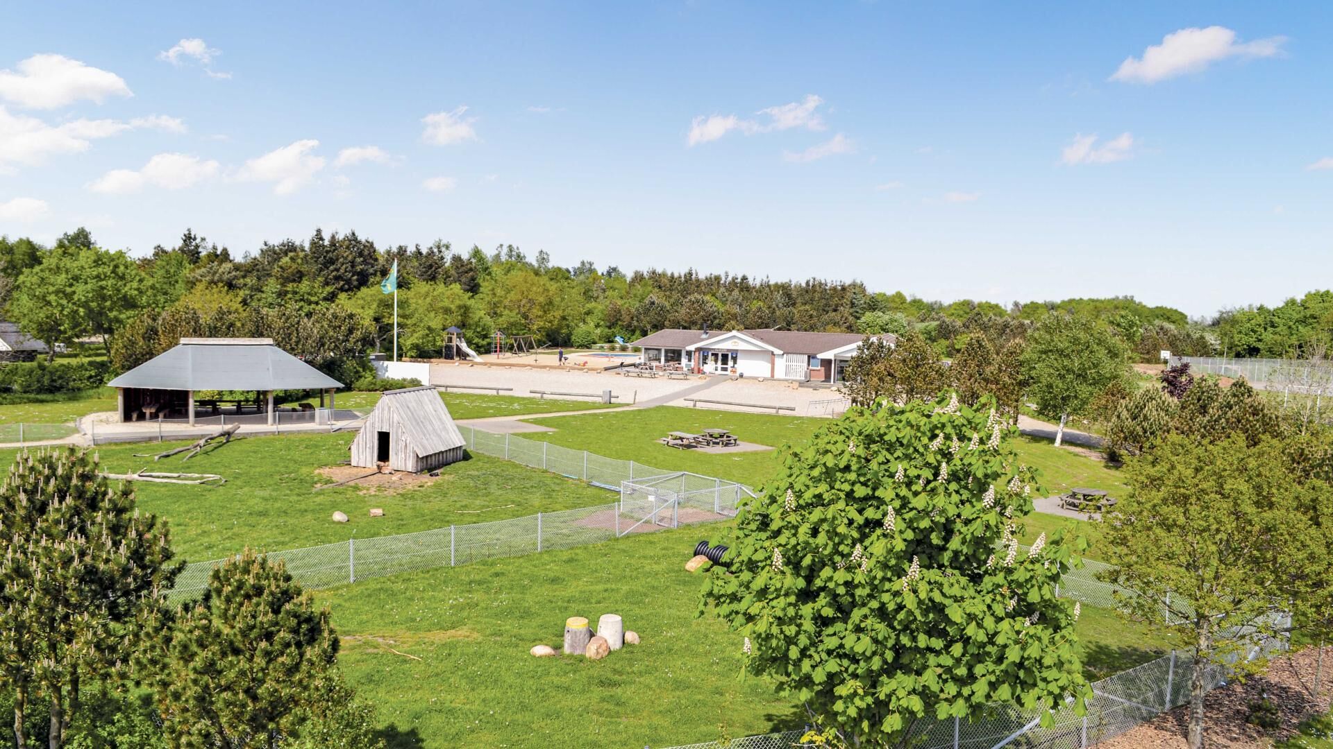 A park with a pavilion, a small shed, and a fenced area with picnic tables.