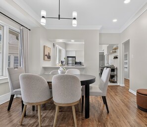 A modern dining area with a round table, four chairs, and a ceiling light fixture. - Spacious House Near American Family Field+State Fair (West Allis)