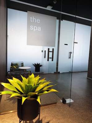 Een modern interieur met een glazen wand, een bank, een bijzettafeltje en een potplant.