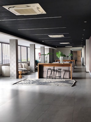 Een ruime woonkamer met een centraal eiland, zitplaatsen en een modern plafondontwerp.