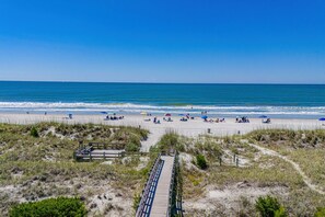 A beach with a wooden boardwalk leading to the shore, sandy beach, and ocean. - Tiki Time - 4BR Beach House w/ Hot Tub + Ocean Views | Sleeps 10 (North Myrtle Beach)