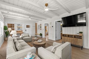 A spacious living room with a large flat-screen TV, multiple seating areas, and a wooden ceiling. - Tiki Time - 4BR Beach House w/ Hot Tub + Ocean Views | Sleeps 10 (North Myrtle Beach)
