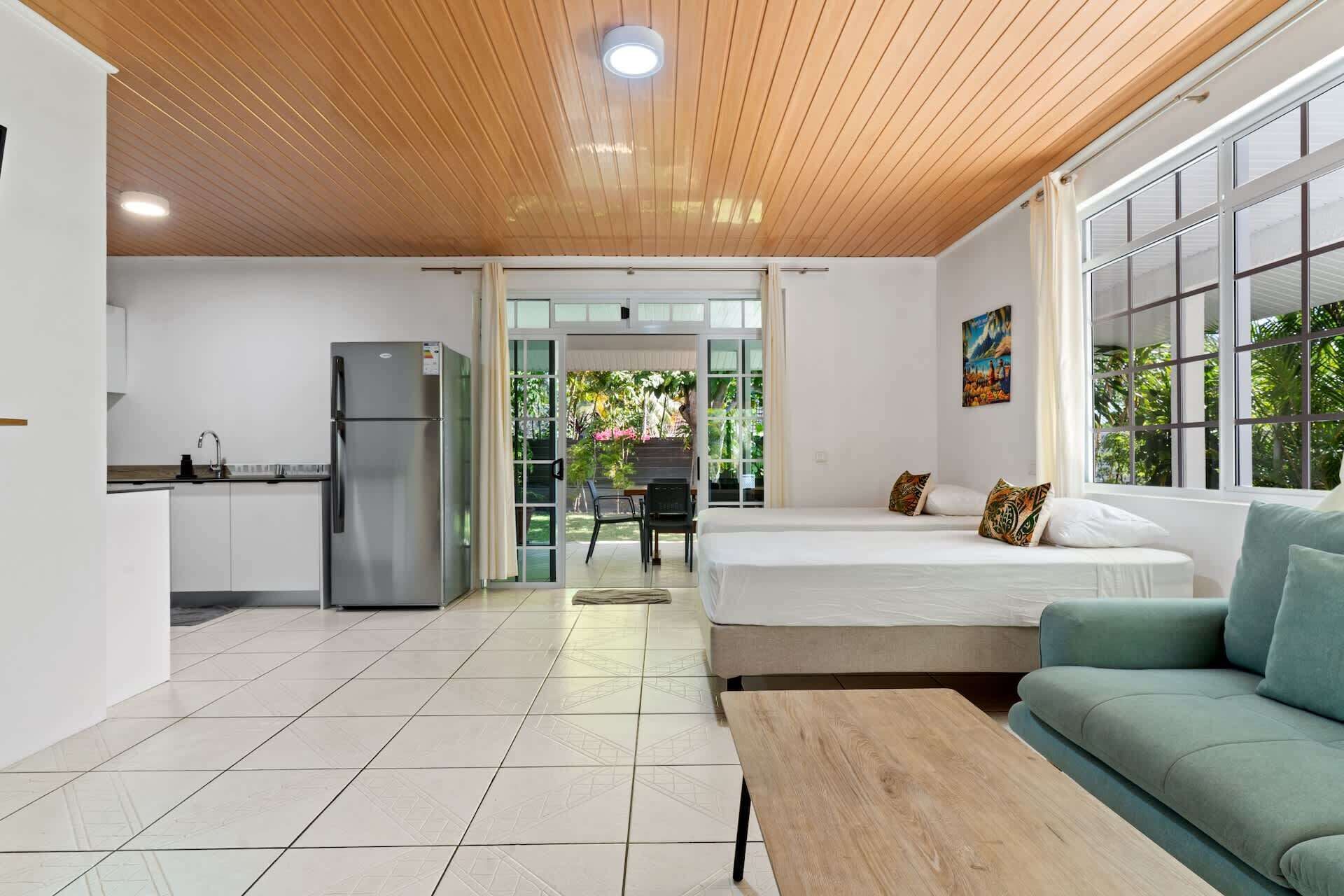 Ein modernes Zimmer mit Bett, Sofa, Esstisch und Küchenzeile.