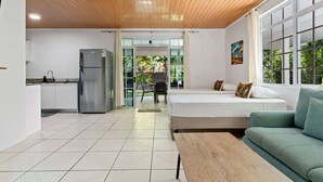 Una habitación moderna con cama, sofá, mesa de comedor y zona de cocina.