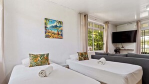 Camera d'albergo con due letti, un divano, una TV e un quadro appeso al muro.