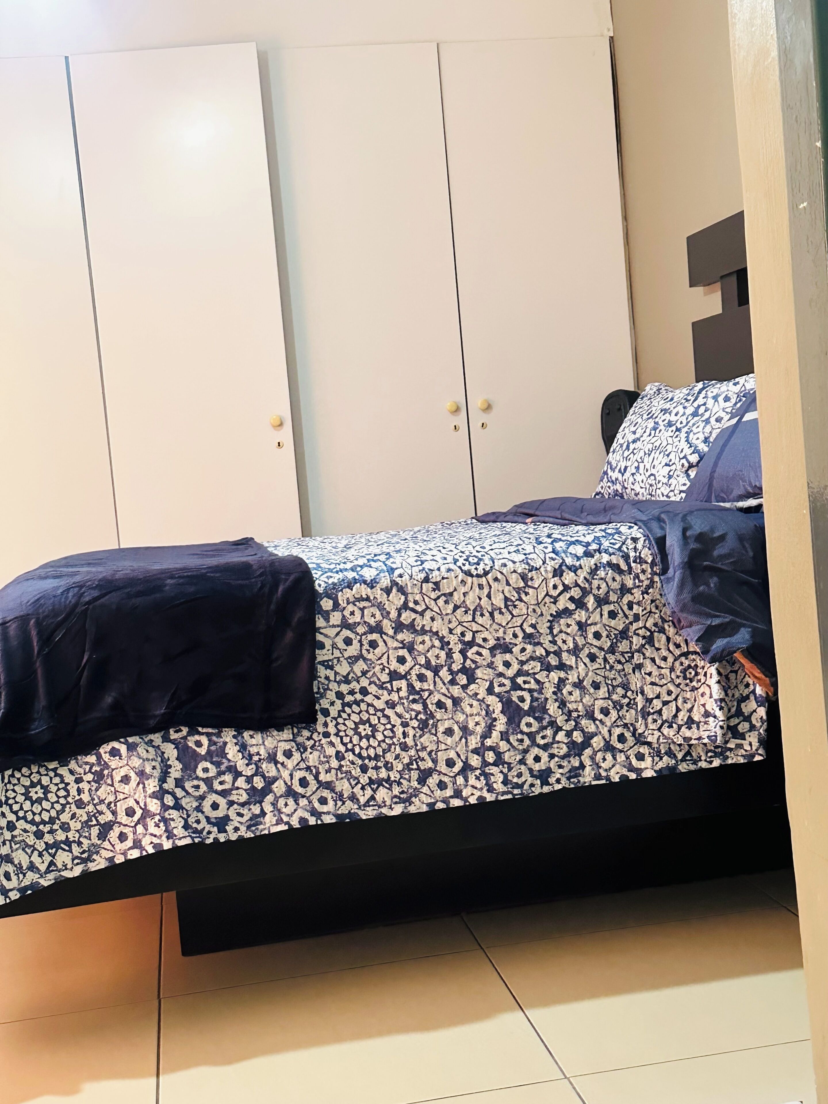 Un dormitorio con cama, armario y mesita de noche.