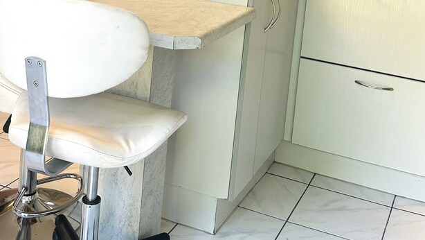 Un baño con tocador blanco, espejo, suelo de baldosas y puerta con motivo geométrico.