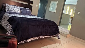 Un dormitorio con cama, ventilador de techo, una puerta y vistas a un balcón.