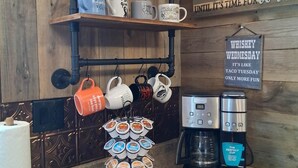 A kitchen with a coffee maker, a mug rack, and a sign about Whiskey Wednesday.