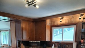 A kitchen with wooden cabinets, a granite countertop, a stove, and two bar stools.