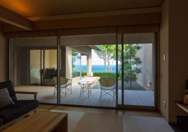 A room with a sliding glass door leading to an outdoor deck with a table and chairs. - OyadoThe Earth (Toba)