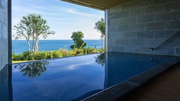 An infinity pool with a clear view of the ocean and trees.
